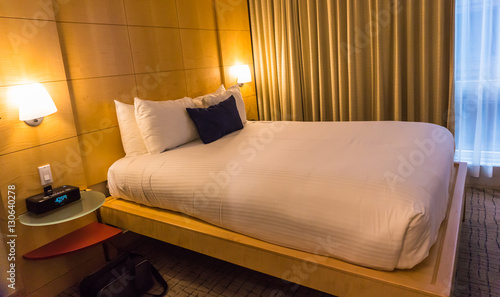 hotel room with queen platform bed, wood en wall, large window, curtains, lights, radio alarm, 