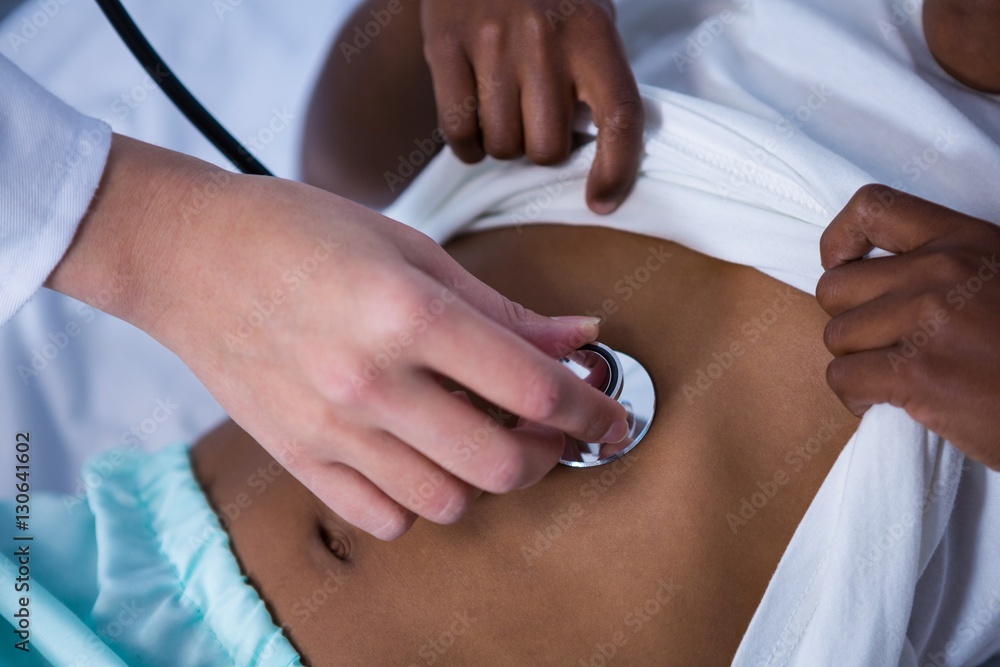Doctor examining patient with stethoscope in ward Doctor examining patient with stethoscope in ward