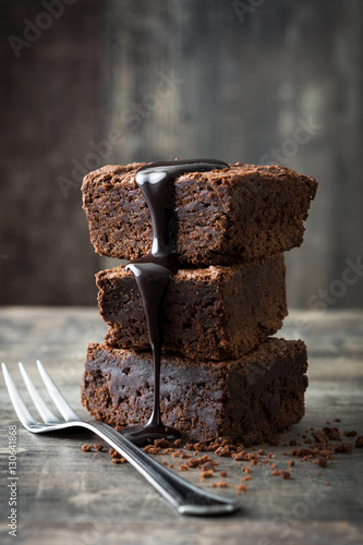 Chocolate brownie with chocolate syrup on wooden background
