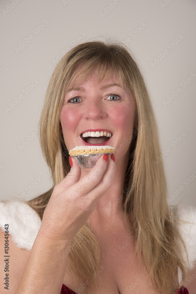 Party hostess eating a Mince pie at Christmastime Party hostess eating a Mince pie at Christmastime