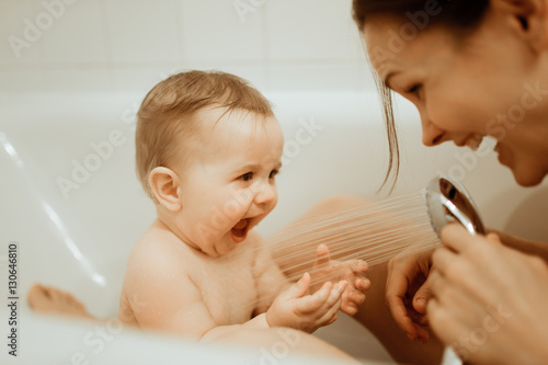 Mother washing shower happy newborn baby in bath