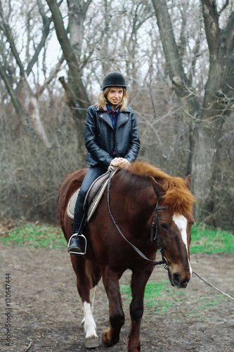 girl smiling while sitting on a horse in the forest © zvkate