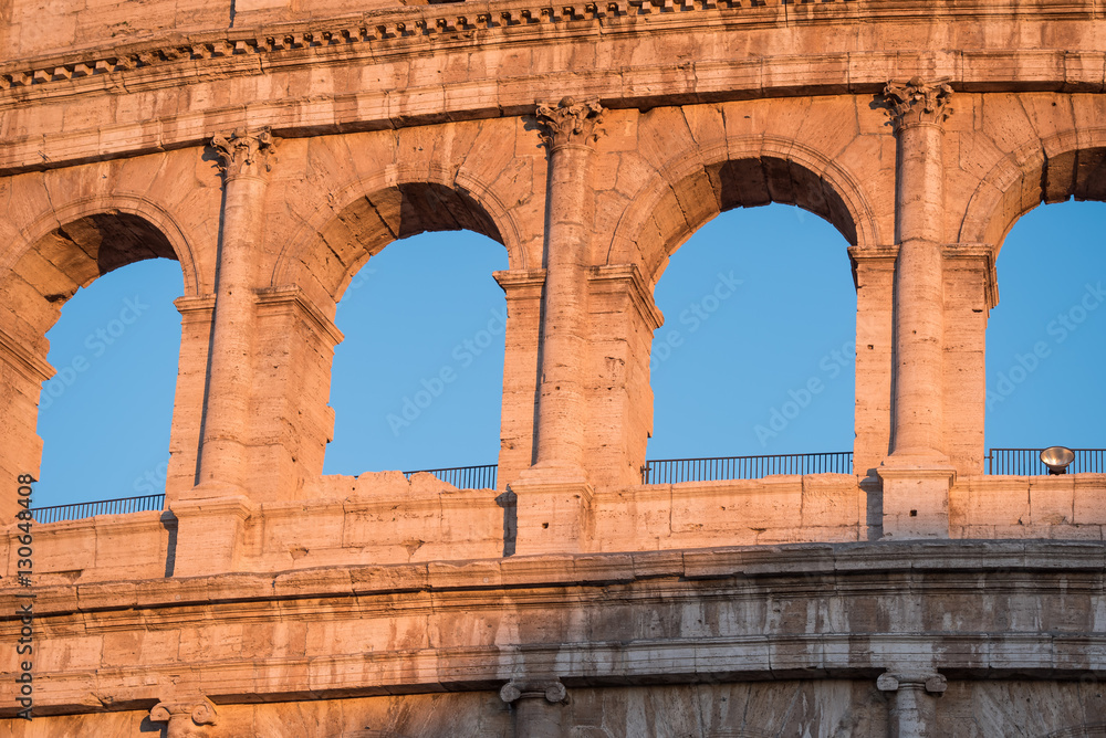 Roman arches at the colosseum lit by sunset