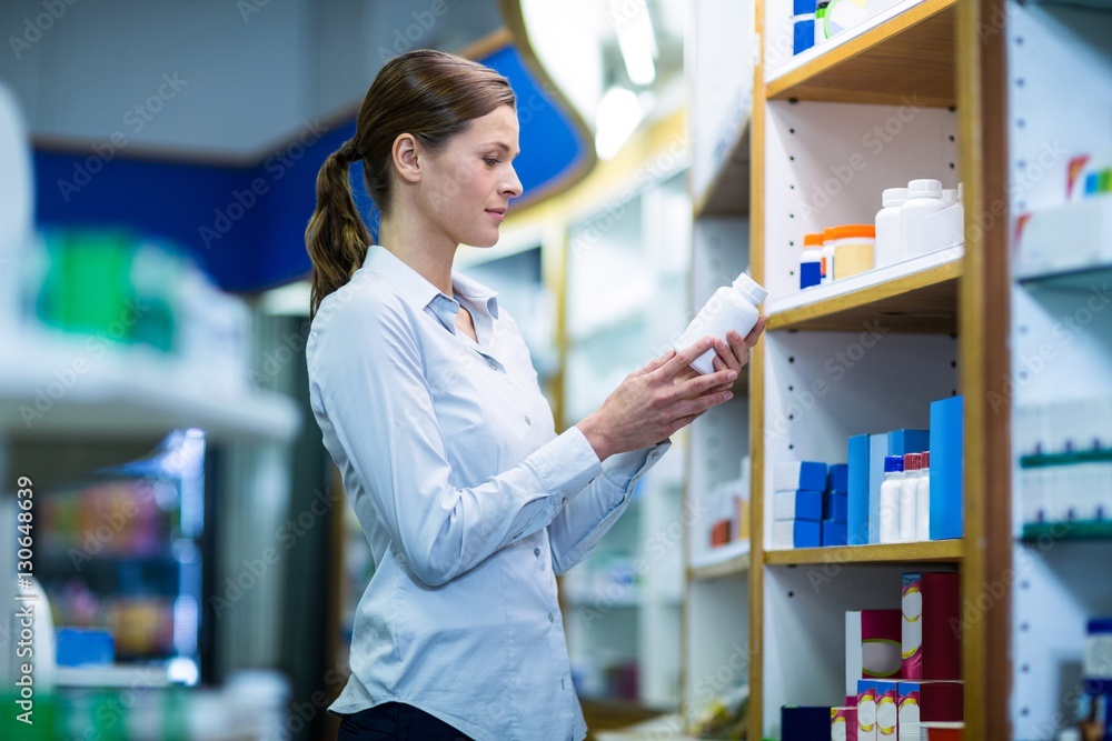 Pharmacist checking a bottle of drug Pharmacist checking a bottle of drug