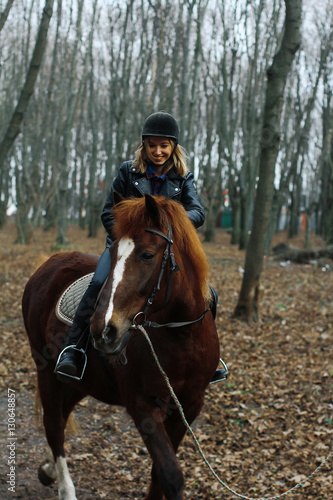 Girl sitting on a horse and laughing at an angle in the woods