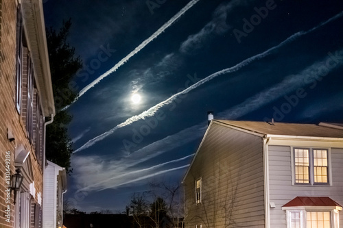 Bright full moon with night sky, airplane trails and homes photo