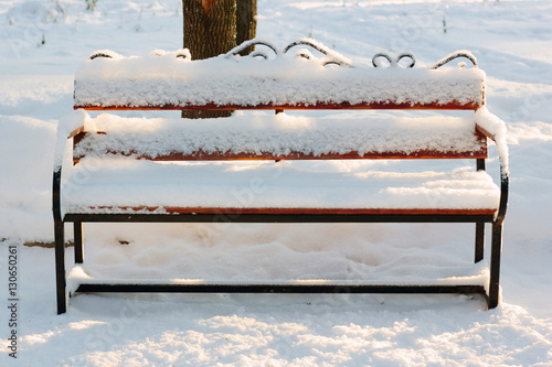 Wooden bench covered by sno...