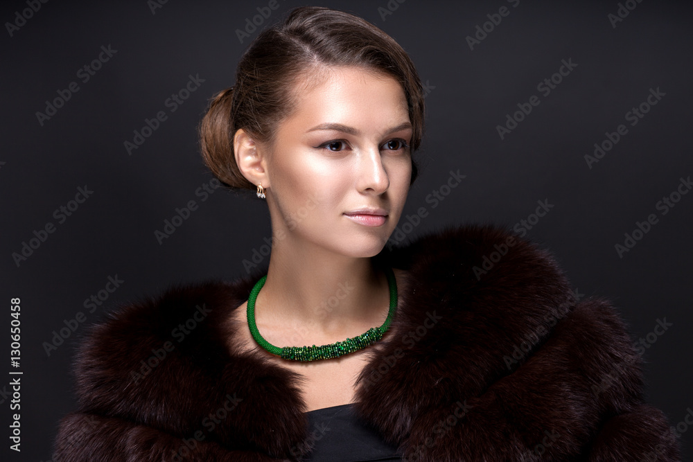 Portrait of a teenage girl in a fur coat on a dark gray backgrou Portrait of a teenage girl in a fur coat on a dark gray backgrou