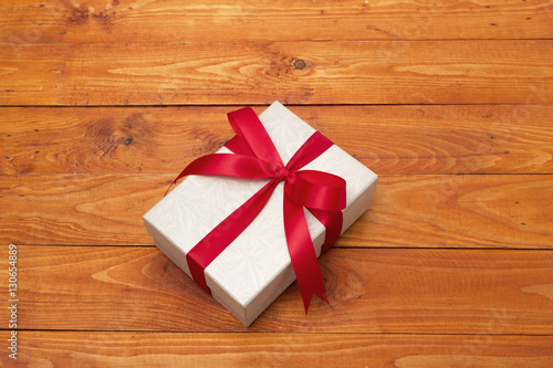 Gift box with red ribbon on wooden table background