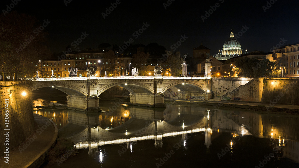 The Vittorio Emanuele Bridge in Rome, Italy, by night. In the background the dome of Saint Peter Basilica.