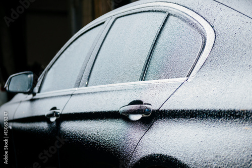 Right side of a luxury car covered with snow at night in the parking