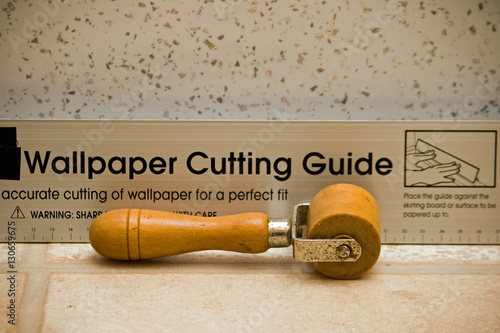 Billede på lærred used wallpaper seam roller and a wallpaper cutting guide with a metal fleck wall
