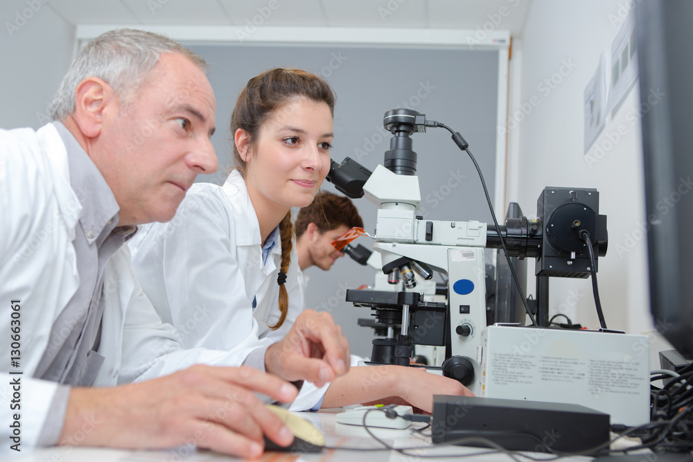 medical students and teacher working with microscope at the university medical students and teacher working with microscope at the university
