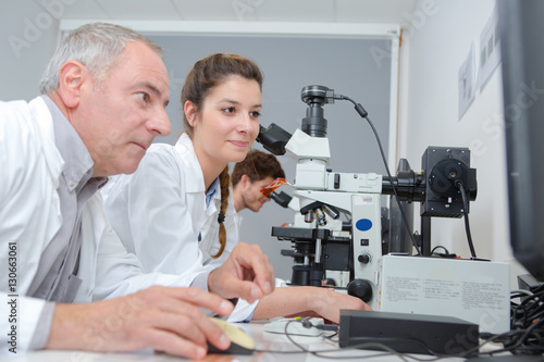 medical students and teacher working with microscope at the university