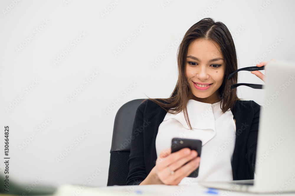 Excited businesswoman winning after achievement reading smart phone sitting in a desktop at office Excited businesswoman winning after achievement reading smart phone sitting in a desktop at office