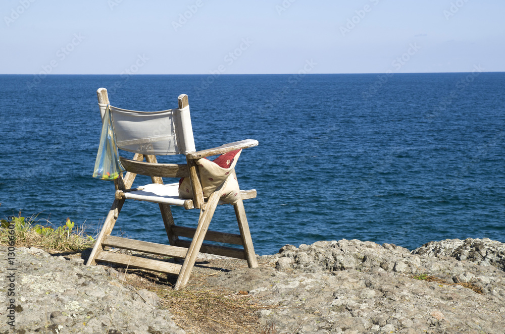 Old wooden chair on a rocky seashore