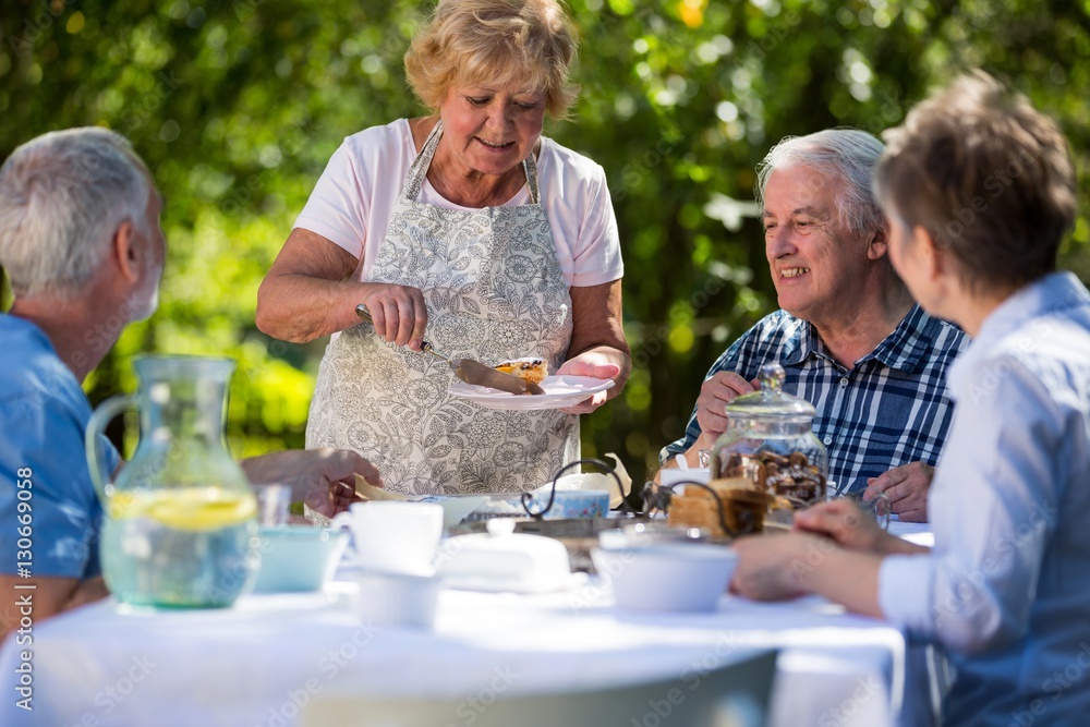 Senior woman serving breakfast in garden Senior woman serving breakfast in garden