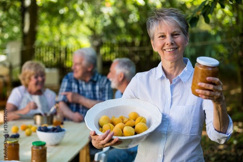 Senior woman holding bottle of jam in garden