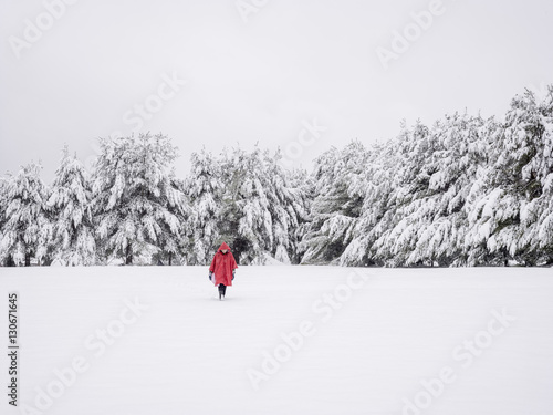 Person in red coat walking through snow in winter