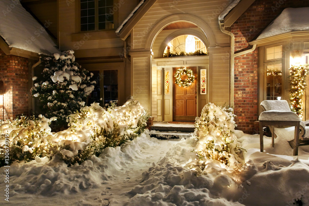 Christmas decorations and lights line front path and patio in the snow