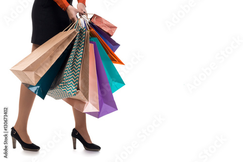 Lower close-up, walking girl holding shopping paper bags and pac