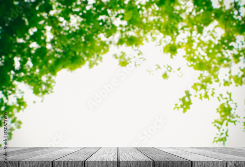 Close up grunge rustic green wooden table top shallow dept of field with sunlight ray of blurred fresh green nature background for products display. © thawornnurak