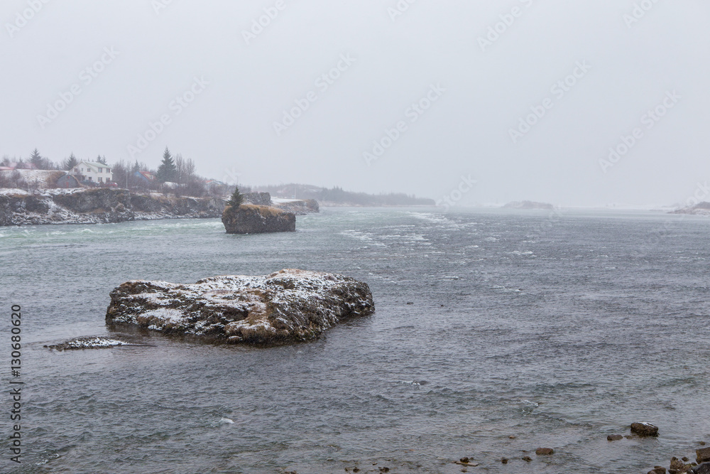 Cold winter blizzard causes heavy snow fall on rocks islands in