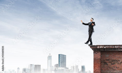 Danger and risk concept with businessman making step from edge