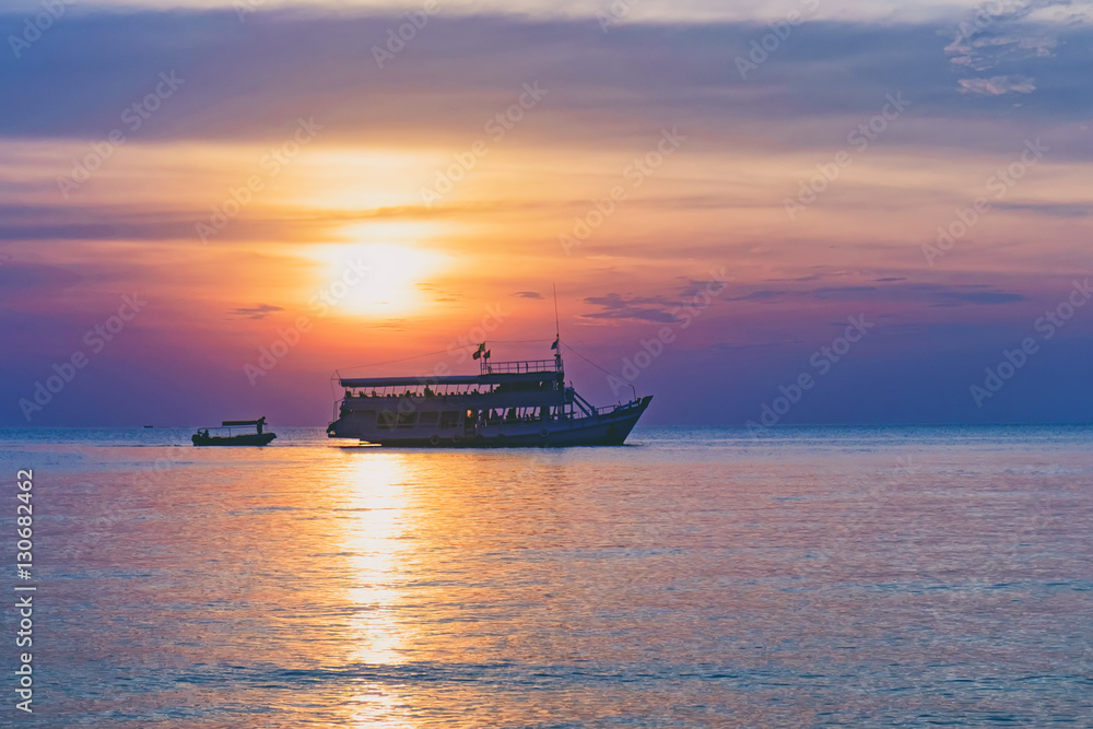 Tropical colorful dramatic sunset with cloudy sky and silhouette of the ship on the horizon. Evening calm on the Gulf of Thailand. Bright afterglow. Tropical colorful dramatic sunset with cloudy sky and silhouette of the ship on the horizon. Evening calm on the Gulf of Thailand. Bright afterglow.