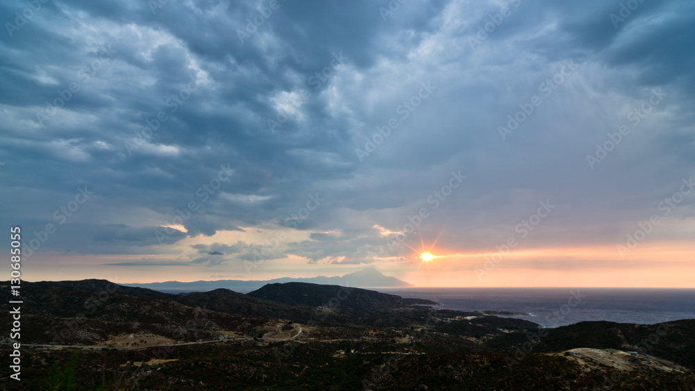Stormy sky, sunrise at sea and landscape around holy mountain Athos in Greece