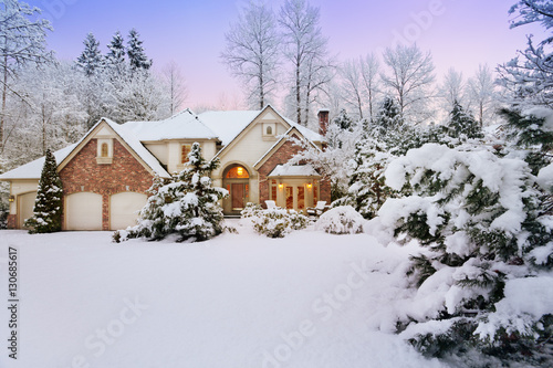 Last light fades as night falls on a snowy suburban home and garden