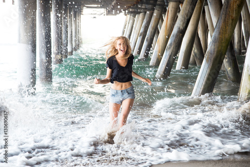 Woman runs from the waves under a pier