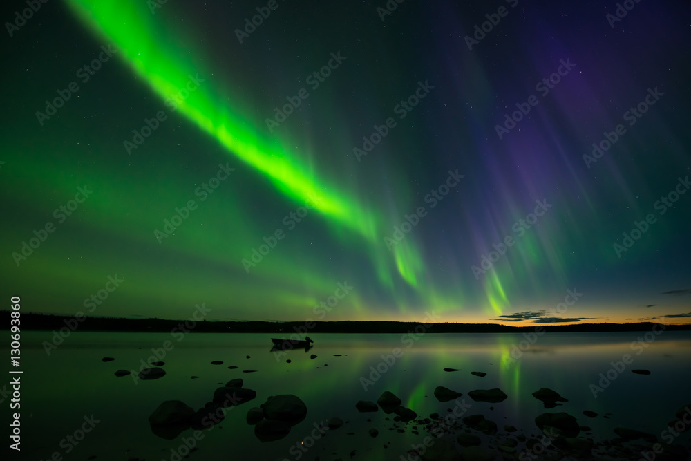 Aurora After Sunset - Colorful bands of aurora borealis appear above a calm lake and lit up the starry sky right after the sun sets.