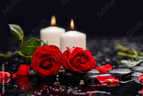 Two red rose with candle  green leaf and therapy stones 