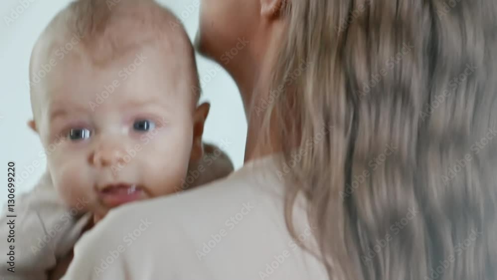 Slow motion with rear view of happy young mother holding baby in arms jumping up and down, then turning back and talking Slow motion with rear view of happy young mother holding baby in arms jumping up and down, then turning back and talking