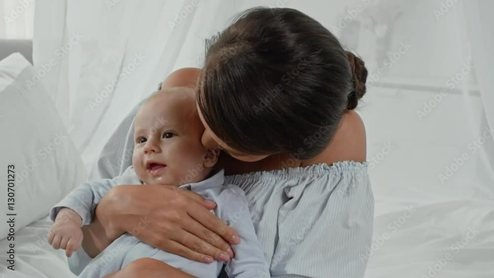 Young mother nuzzling cute little baby sitting on her lap Young mother nuzzling cute little baby sitting on her lap