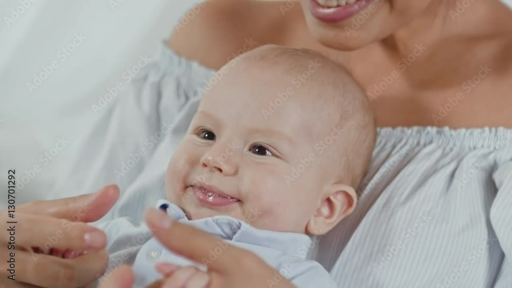 Adorable baby boy sitting on his mother and laughing Adorable baby boy sitting on his mother and laughing