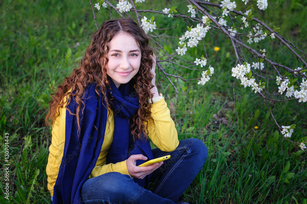 beautiful young woman sitting on the grass with phone beautiful young woman sitting on the grass with phone