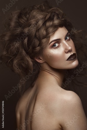 Beautiful girl with creative hairstyle art, perfect skin and dark makeup. The beauty of the face. Portrait shot in the studio.