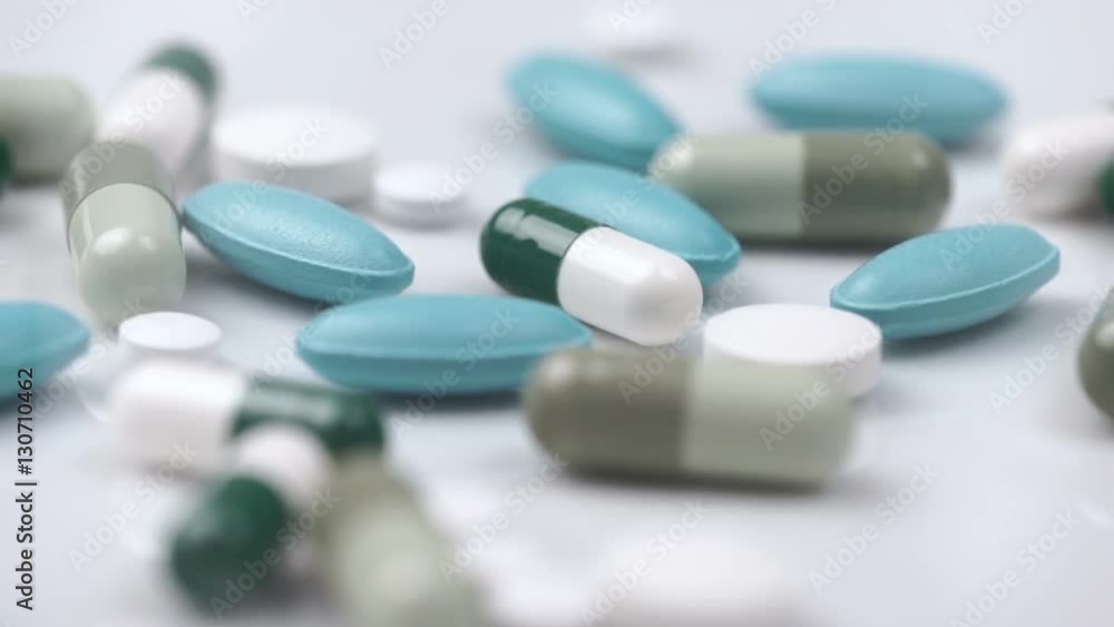 White green pills rotate on a white background White green pills rotate on a white background