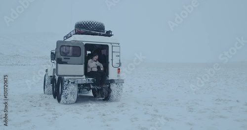 A young man sitting in trecol car and searching network on smartphone.  Red Epic 4k photo