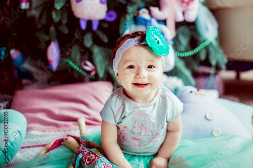 The smilling baby sits near Christmas Tree