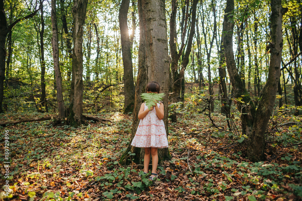little girl standing in the forest with ferns
