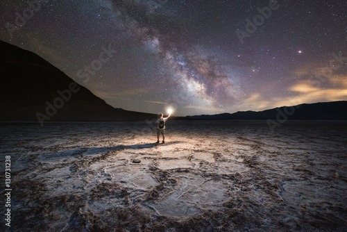 Man light painting Badwater Basin under the Milky Way Galaxy