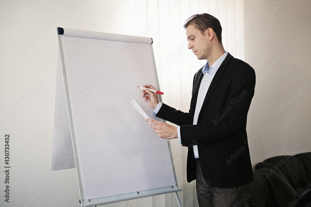 Male adult man in a suit standing next to the white board, looki Male adult man in a suit standing next to the white board, looki