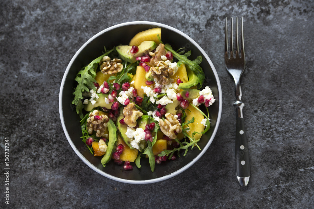 Bowl of avocado salad with rocket, pomegranate seed, kaki, feta and walnuts Bowl of avocado salad with rocket, pomegranate seed, kaki, feta and walnuts