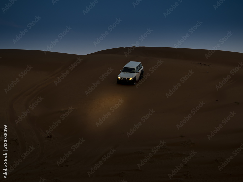 Oman, Al Raka, off-road vehicle parking on dune in Rimal Al Wahiba desert at twilight Oman, Al Raka, off-road vehicle parking on dune in Rimal Al Wahiba desert at twilight