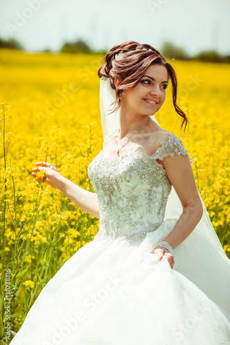 young and beautiful bride in white dress walking in the field