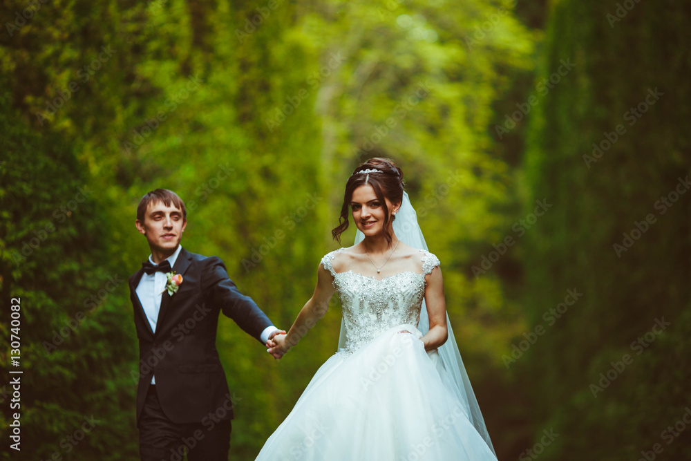 handsome and young groom and his beautiful bride walking in the