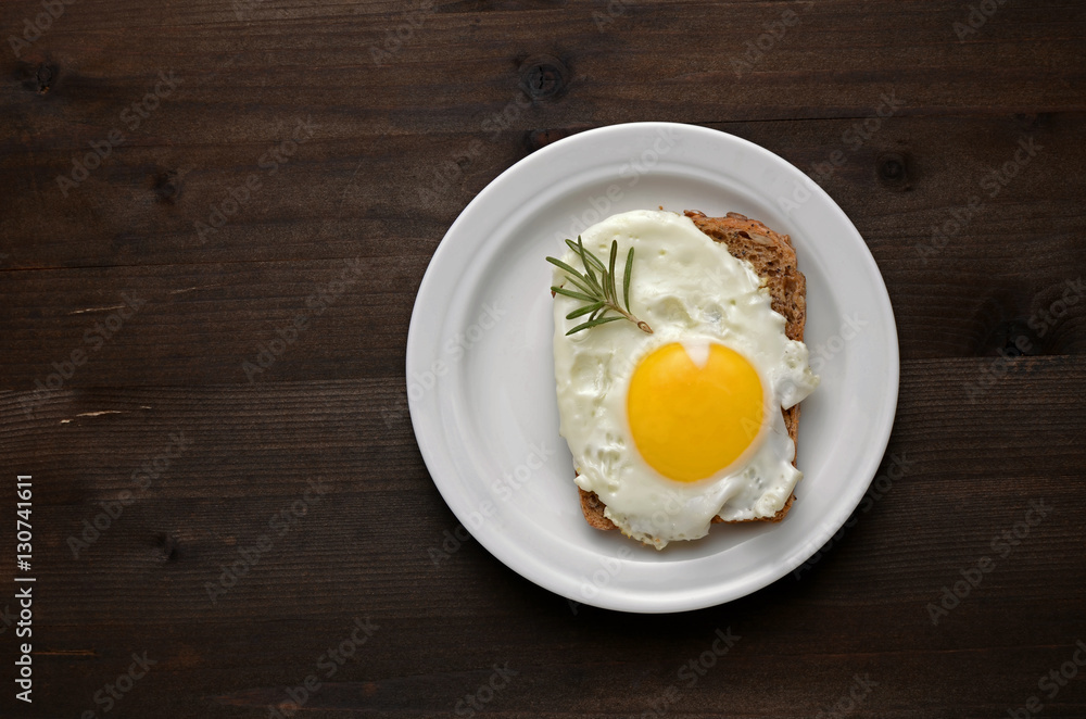 fried egg with rosemary on a white plate fried egg with rosemary on a white plate